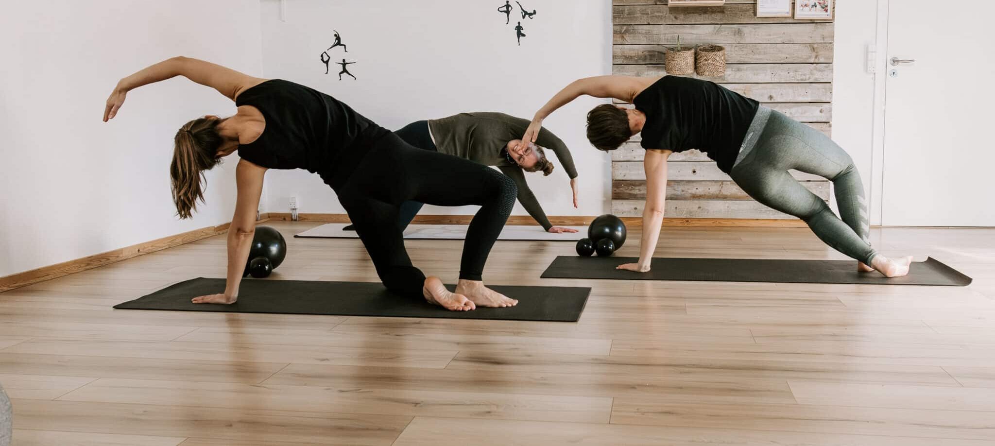Mediyoga eller pilates undervisning i Assentoft. To kvinder udfører under kyndig vejledning en øvelse, som kræver fokus på styrke, balance og dyb koncentration.